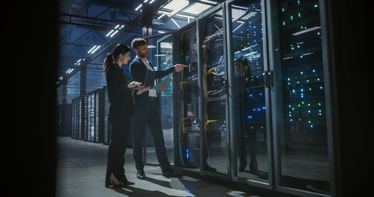 Two IT specialists inspecting server racks in a data center